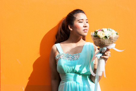 asian lady in wedding dress suite hold bouquet on yellow backgroundの写真素材
