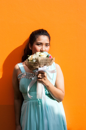 asian lady in wedding dress suite hold bouquet on yellow backgroundの写真素材