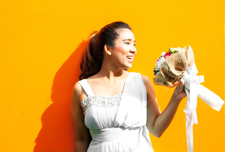 asian lady in wedding dress suite hold bouquet on yellow backgroundの写真素材