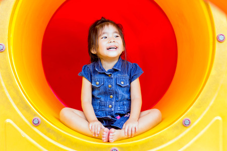 close up cute asian girl play in outdoor toy park turnel at playgroundの写真素材