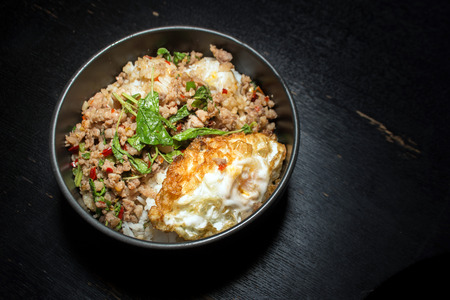 Thai faverite food pork fried rice and fried egg with basil and chili on dark wood tableの写真素材