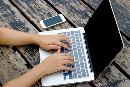 focus hand typing laptop on wood table and mobile