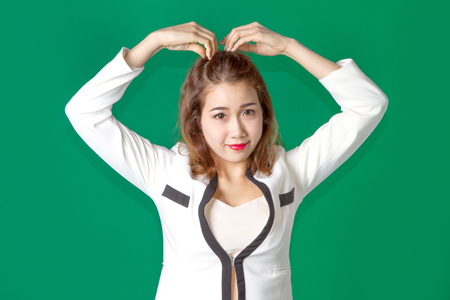 asian thai lady acting arm on head like heart symbol in businees wearing on green screenの写真素材