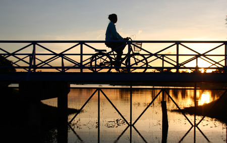 silhouette house wife bike on the bridge in sunrise for fresh market