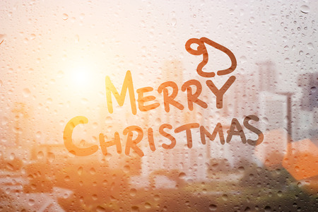 draw merry christmas word with raining in morning light sunset on mirror and town landscapeの写真素材