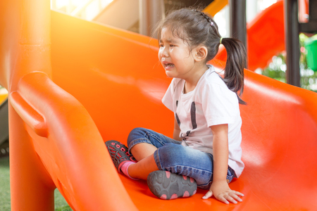 asian Thai girl kid crying with slider outdoor playgroundの写真素材