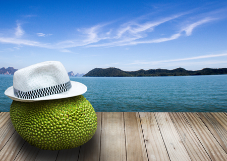 jackfruite with hat on wood top floor before landscape clear ocean summer concept