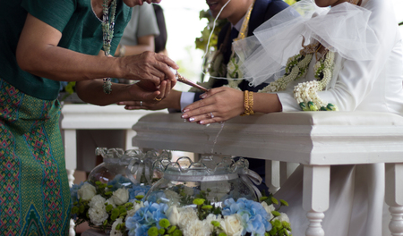 close up hand of parent praying with water to blasing to groom and bridge hand in thai wedding ceremonyの写真素材