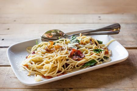 close up spagetti with crispy bacon and vegetable serve on wood table in italian food restaurantの写真素材