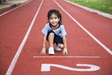 asian girl ready to start running game on the line of outdoor arenaの写真素材