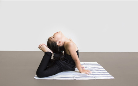smiling asian girl do yoga action on matt in balance position