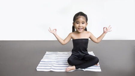 smiling asian girl do yoga action on matt in sitting positionの写真素材