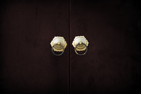 ancient asian doorknob decoration on red wood gate for background in dark concept の写真素材