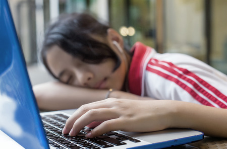 select focus hand of sleeping asian girl with computer is behavior of digital generation  の写真素材