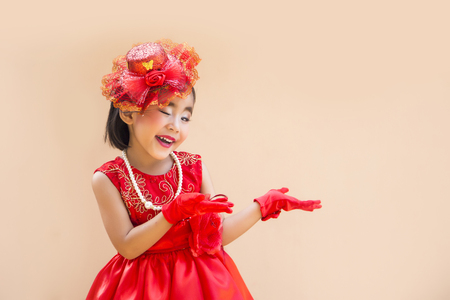 cute asian girl with red vintage costume show hand action on cream color screenの写真素材