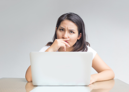 asian woman use laptop and mobile in busy action laptop screen to display content inside with unhappy feelingの写真素材