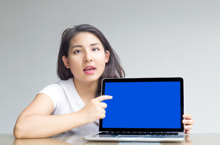 asian woman point to blank laptop screen to display content inside with unhappy feelingの写真素材