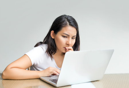 asian woman serious action use laptop to find something の写真素材
