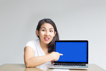 asian woman point to blank laptop screen to display content inside with unbelive action on tableの写真素材