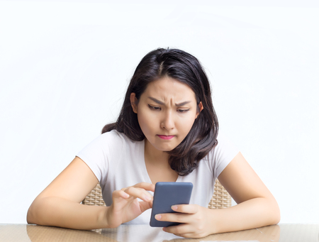 asian woman touch on mobile with serious feeling with outdoor tableの写真素材