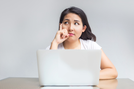 asian woman point up with laptop with thinking ideaの写真素材
