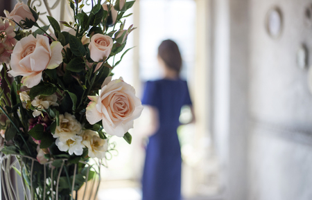 focus artificial bush orange rose decoration home and blur woman standing window in morning light in vintage colour tyleの写真素材