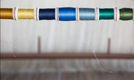 Focus color reel on blur weaving machine on background. Textile craftsmanship concept