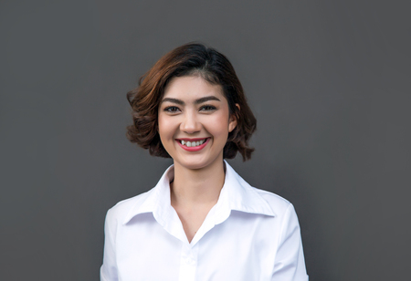 Pretty smiling joyfully asian female with curly short hair, dressed casually, looking with satisfaction at camera, being happy. Studio shot of good-looking beautiful woman against.の写真素材