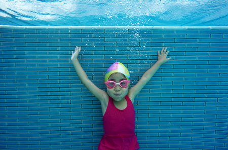 asian kid swimming underwater in summer. Outdoor activities in swimming pool. Zoom motion in poolの写真素材