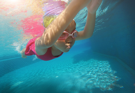 asian kid practice swimming underwater in summer. Outdoor activities in swimming pool. Zoom motion in poolの写真素材