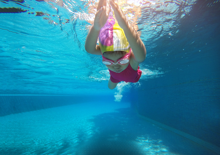 happy asian kid swimming underwater in summer. Outdoor activities in swimming pool. Zoom motion in poolの写真素材