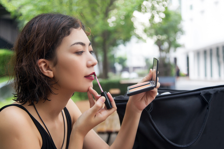 close up shot beautyful lady use lipstick to make up her face with mirror. Beauty and fashion Conceptの写真素材