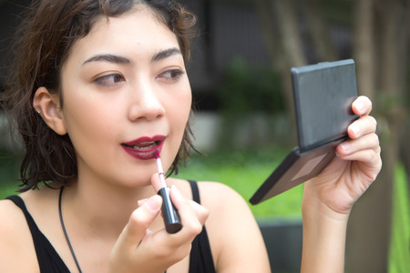 close up shot beautyful lady use lipstick to make up her face with mirror. Beauty and fashion Conceptの写真素材
