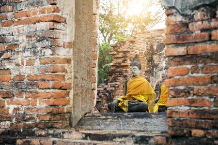 buddha figure behind wood window on old red brick at ancient temple in Thailand.の写真素材