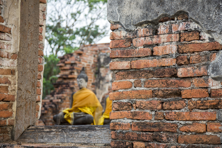 close up old red brick wall with open wood window to see buddha figure at ancient temple in Thailand.の写真素材