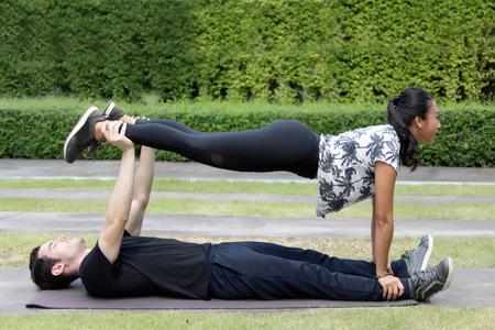 asian woman and trainner do panking yoga position on park for healthyの写真素材