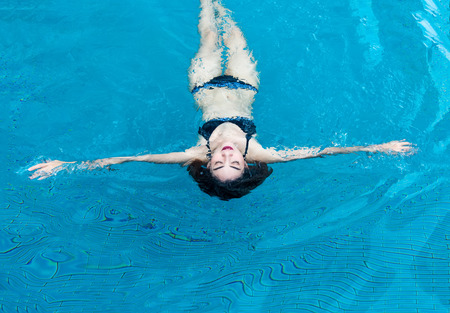asian lady in swimming suite playing water posting on water pool. Relax in holiday conceptの写真素材