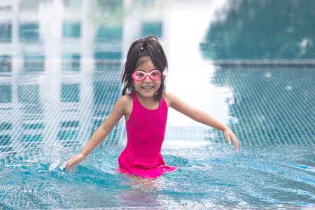 cute smile asian kid love to play on water pool in swimming suiteの写真素材