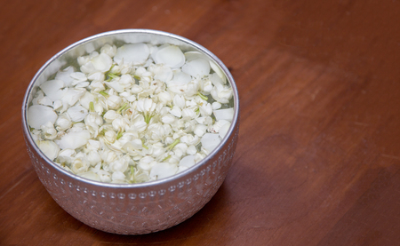 aroma water with jasmine flower in silver bolw on wood table background from top viewの写真素材