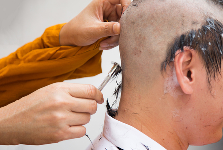 close up shot Buddha monk shave hair on man head in prietst ceremony.の写真素材