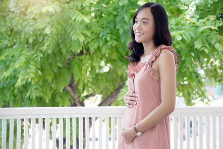 asian lady carry pregnancy new baby at balcony . First time baby concept.の写真素材