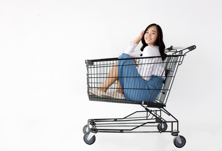 happy asian girl in shopping with shopping cart and shopping paper bagの写真素材
