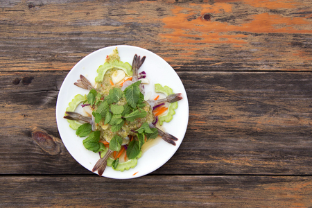 serve raw shrimp with seafood chilli sauce, mint leaf and vegetable on wood table from top viewの写真素材