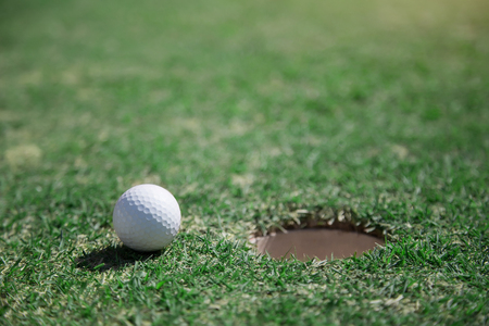 golf ball close to hole on green grass field. close to goal target concept with golf sport caption.の写真素材