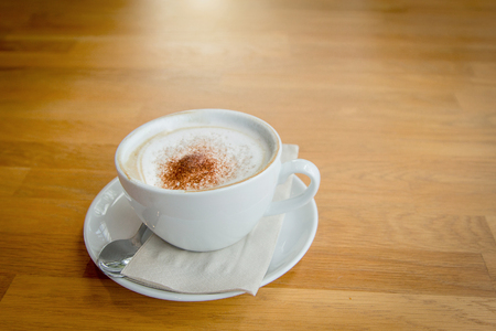 warm cappucino coffee on cup on wood table from top view. hot coffee beverage for fresh upの写真素材