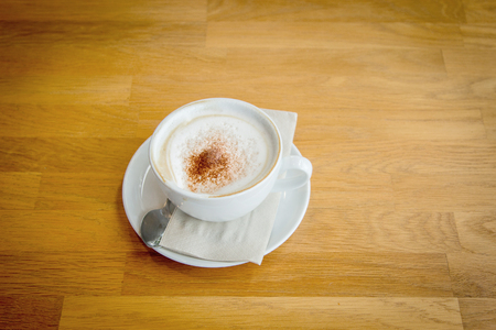 warm cappucino coffee on cup on wood table from top view. hot coffee beverage for fresh upの写真素材