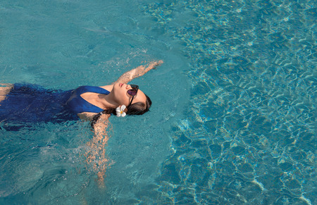 asian girl with swimming suite and sun glasses relax on swimming pool.Relax lifestyle with water concept.の写真素材