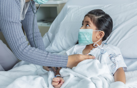 doctor heal Influenza A virus or H1N1 flu asian kid on hospital bed. Medicine virus situation when kid have high fever. Doctor use stethoscope to hear pulpの写真素材