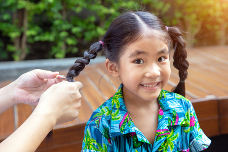 parent make pigtail asian kid hair at park. Family moment with childrenの写真素材