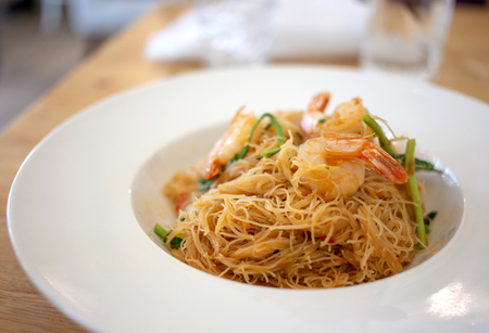 asian thai food noodle with shrimp and vegetable serve on white ceramic dish on wood tableの写真素材